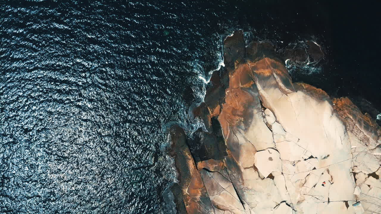 Aerial footage of a rocky peninsula jutting out into the sparkling Atlantic Ocean along the shoreline of Nova Scotia, Canada