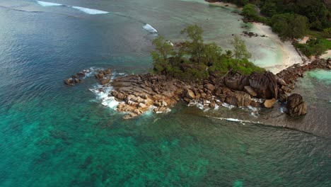 Drone-moving-towards-rock-boulders-near-the-beach-of-Port-glaud-Mahe,-Seychelles-Slow-motion