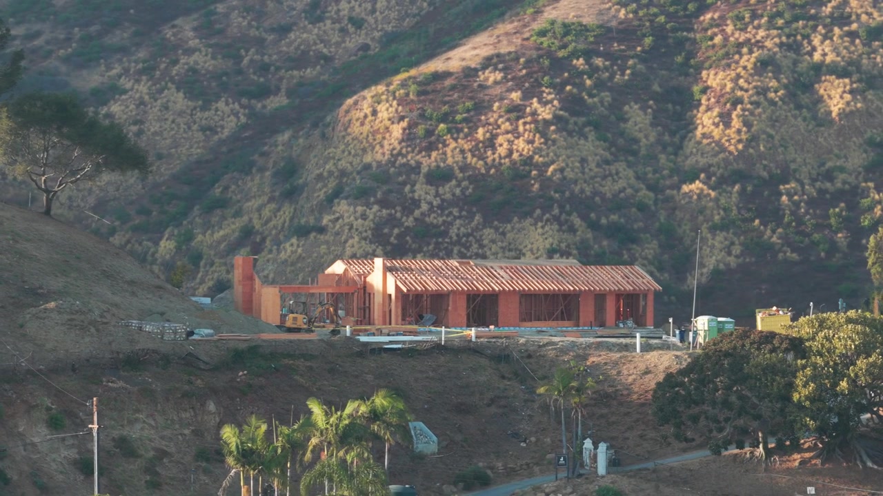 Carrellata aerea con teleobiettivo di una nuova casa in ricostruzione a Carbon Canyon dopo l'incendio in Malibu, California. 4K.