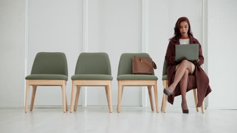 woman working on laptop while waiting in a room