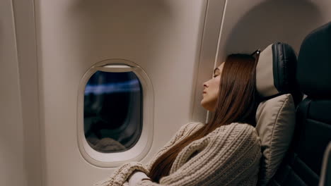 woman sleeping on airplane window seat