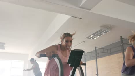 Determined-unaltered-diverse-women-training-on-elliptical-bikes-at-gym-fitness-class,-in-slow-motion