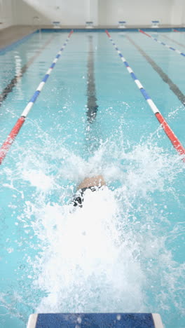 vertical video: swimming in pool, water splashing in lane, competitive swimming training