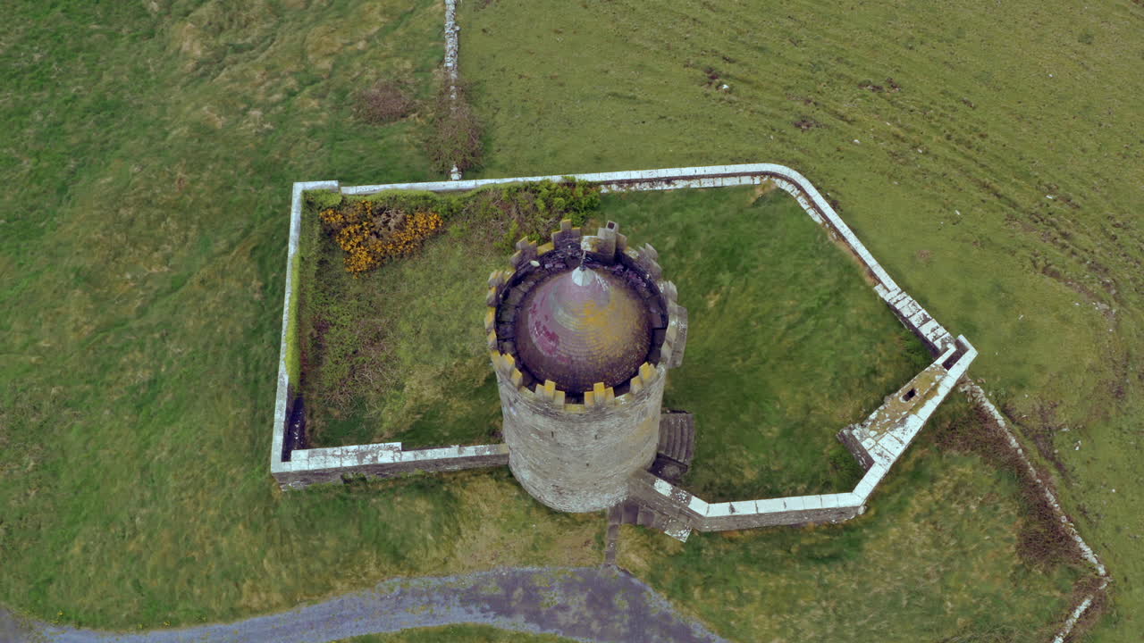 Ascending aerial beautifully reveals Doonagore Castle layout from top down view. Doolin, Ireland