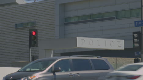 street view of police station with traffic featuring moving cars and a car stopped on red signal