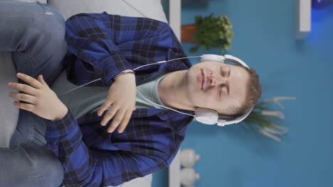 Vertical-video-of-Man-listening-to-music-with-headphones-is-unhappy-and-sad.