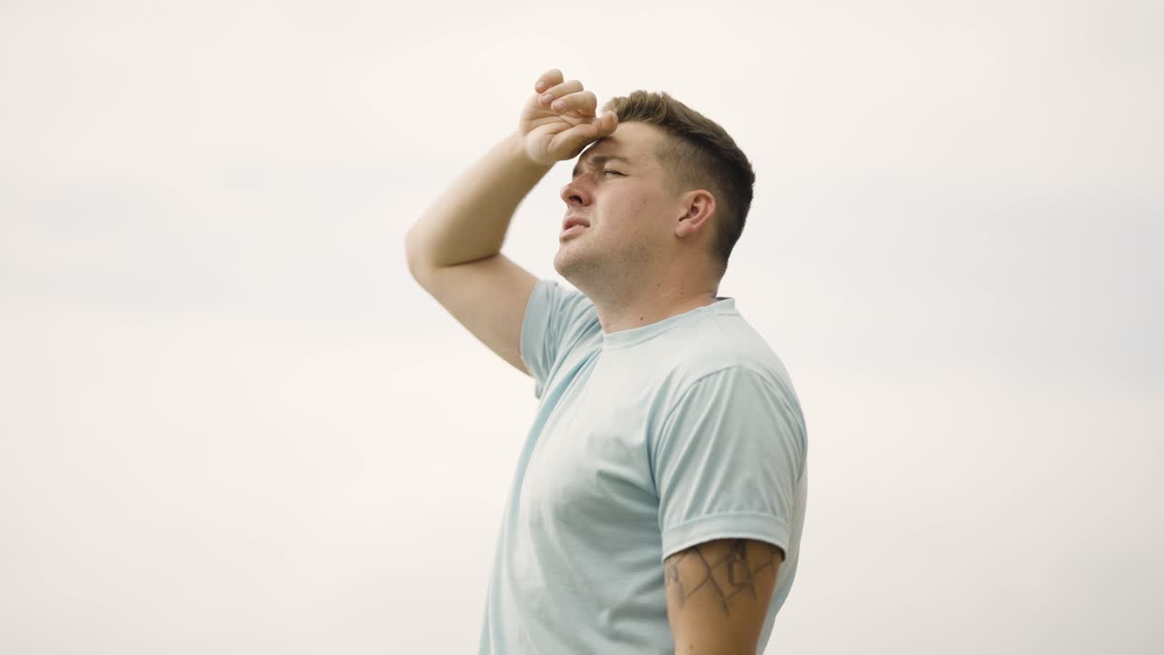 말리부 해변에서 하늘을 바라보는 남자가 태양을 가리는 눈을 넘겨