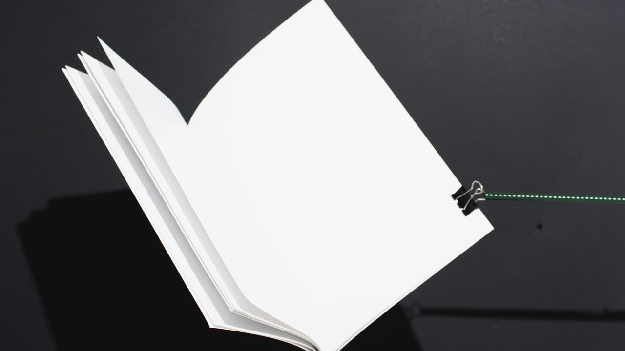 Video of book with string and white blank pages and copy space on black background