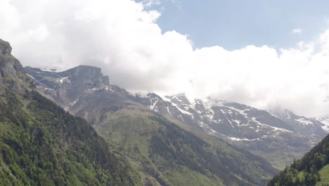 Tilt-up-from-beautiful-green-valley-to-clouds-rolling-over-high-mountains