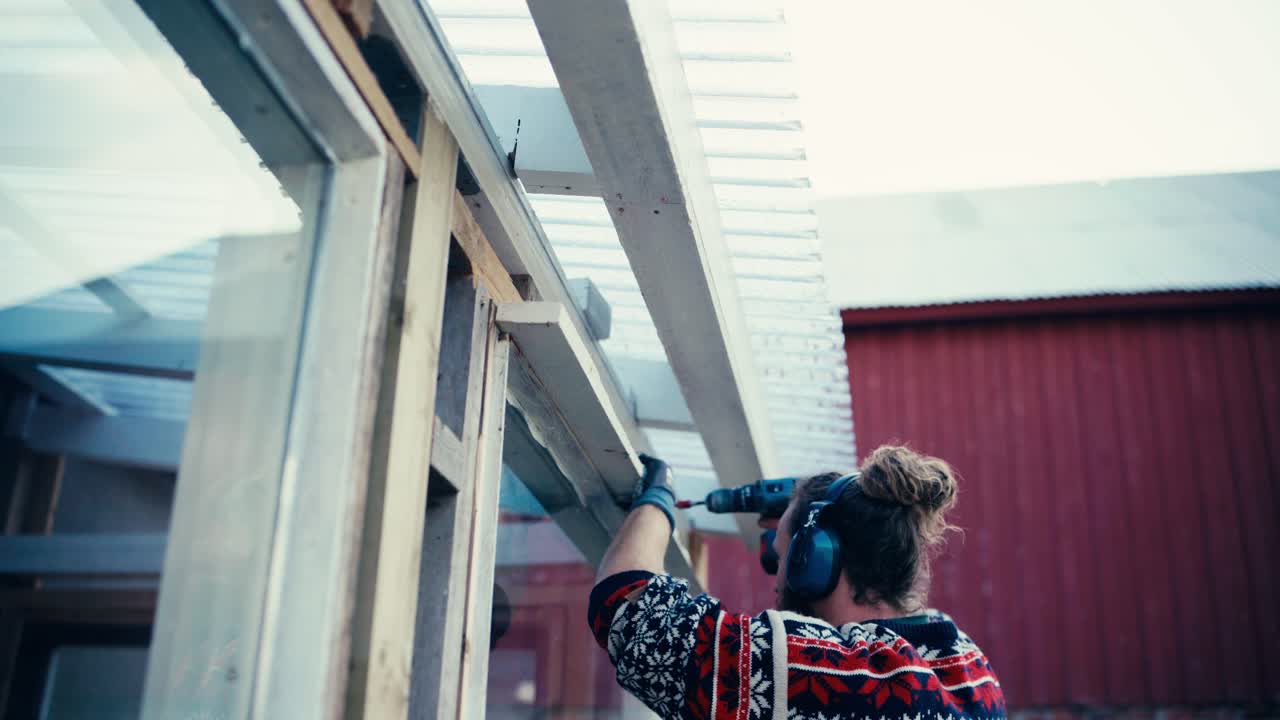 Mann som borer hull i vinduskarm med batteridrill