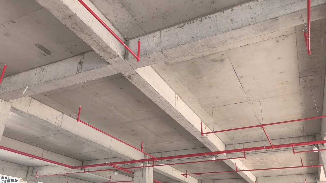 Workers install a fire sprinkler pipe network at a construction site. Fabricated to precise engineering designs, this vital system delivers water to suppress initial blazes before firefighters arrive.