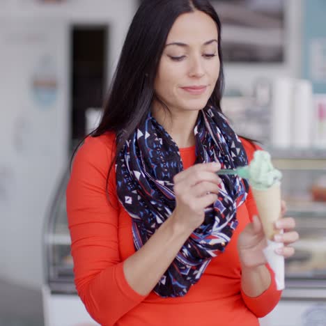 mujer joven sonriente saboreando un cono de helado