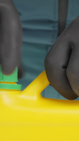 person opening a yellow chemical container with protective gloves