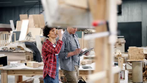 people walking in workshop talking discussing work holding coffee and tablet