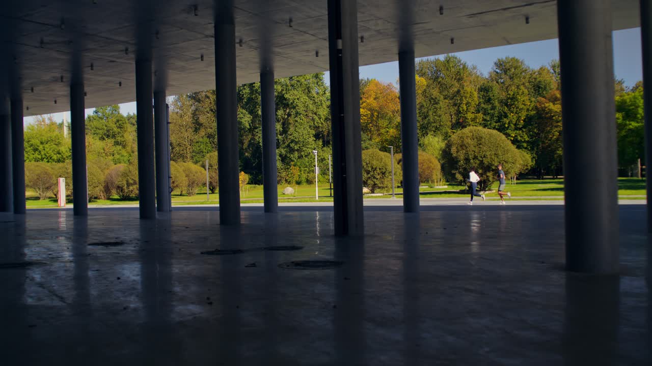 Urban park with people running under concrete columns