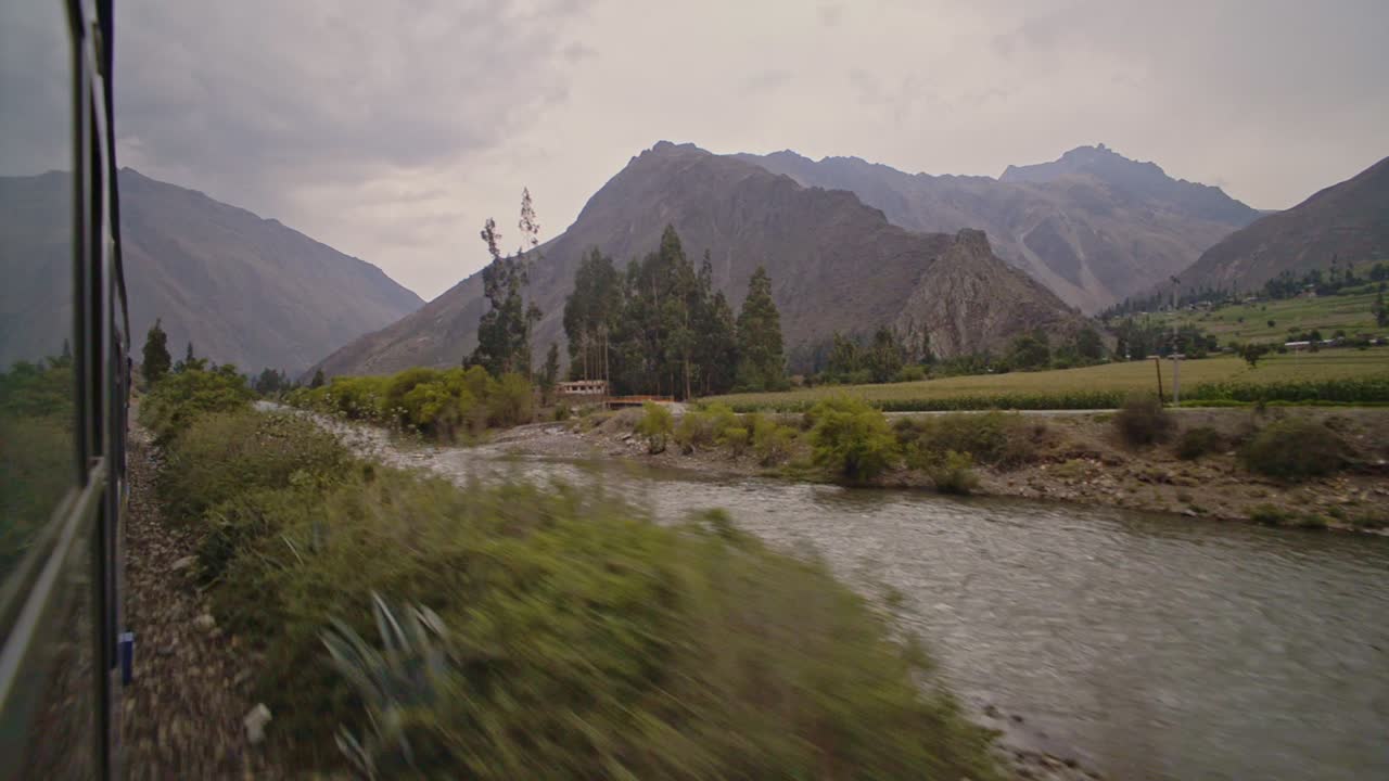 Mountains landscape view over a river, from a train window, from Cusco to Machu Picchu, Peru, at dusk