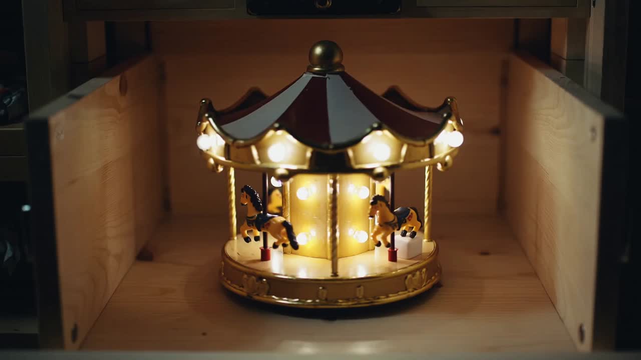 Rotating small carousel music box turning inside wooden drawer, motor driving painted horses, bulbs