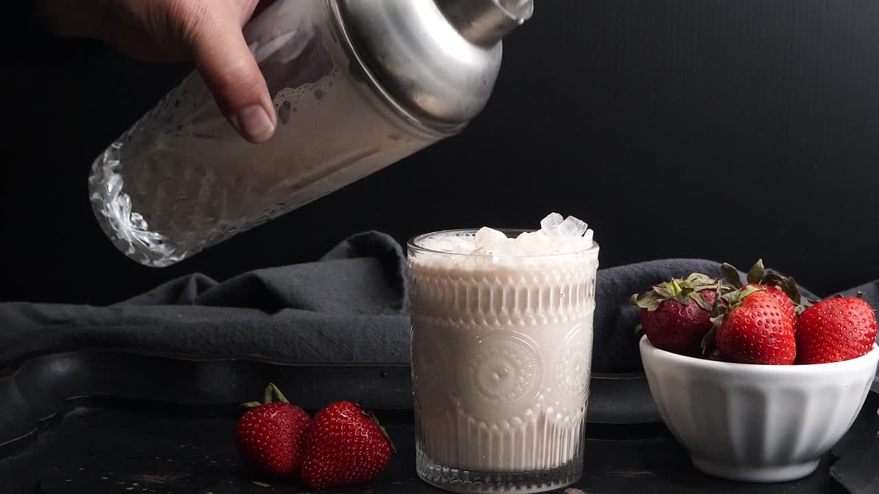 Pink cocktail drink with strawberry liqueur, vanilla vodka and cream. Party drink with strawberries. Fruit cocktail with fresh strawberries as a garnish. Cold and refreshing