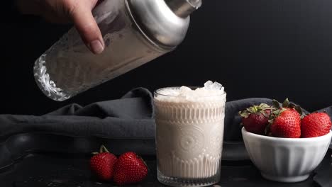 pink cocktail drink with strawberry liqueur, vanilla vodka and cream. party drink with strawberries. fruit cocktail with fresh strawberries as a garnish. cold and refreshing