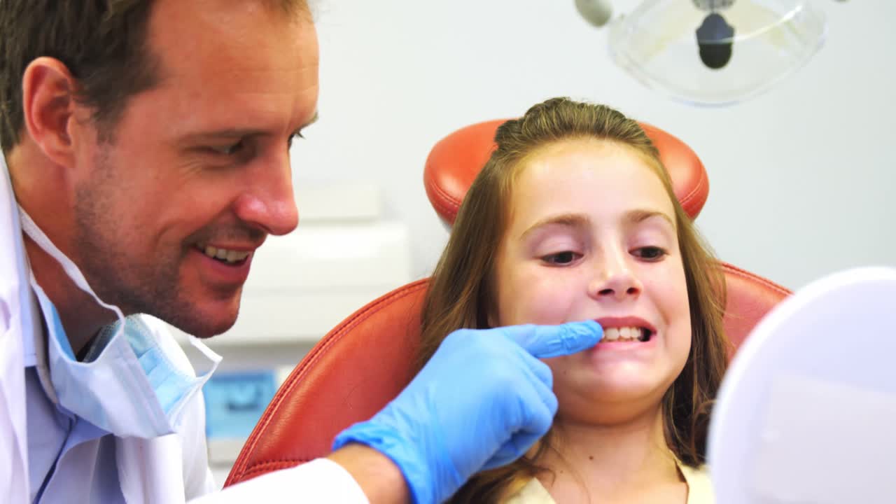 Dentist showing girls teeth on mirror