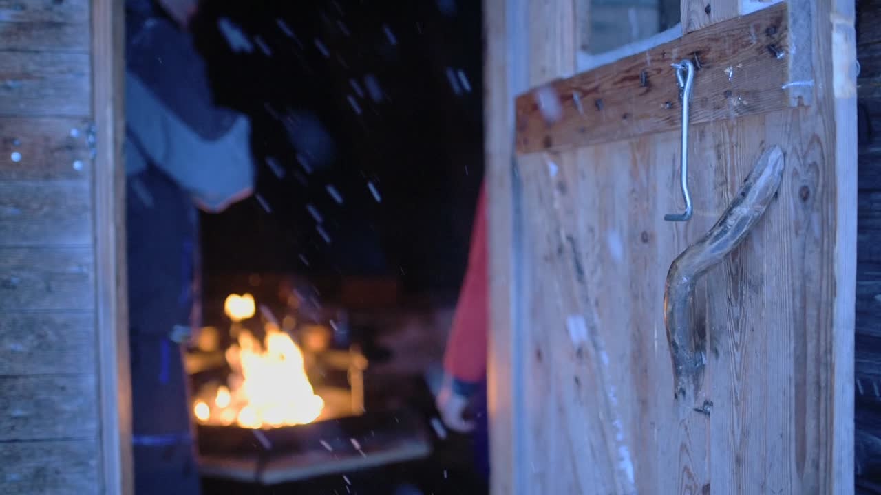 People warming up around a fireplace, on a snowy evening, in Lapland, Finland