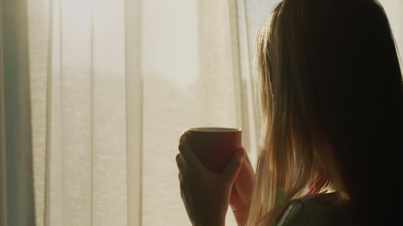 뒷면: 뜨거운 차 한 잔 을 들고 있는 여자 가 태양 이 뜨는 창밖 을 바라보고 있다. 뜨거운 음료 와 좋은 기분