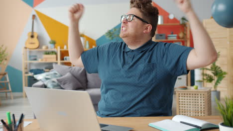 man excitedly reacts to something on laptop
