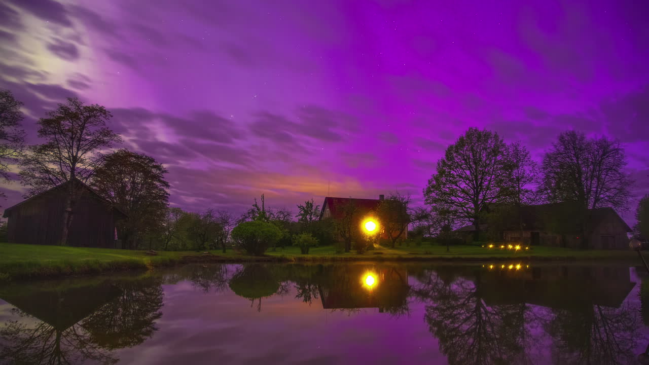 nubes que pasan en un cielo púrpura sobre cabañas cerca de una orilla del lago