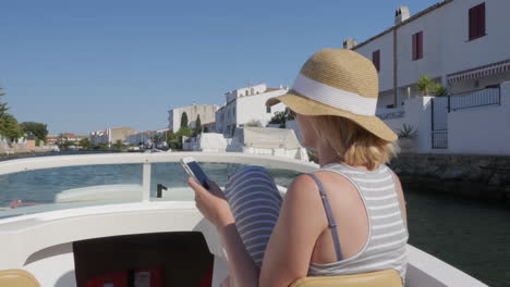 empuriabrava spain young tourist with a hat floating on a boat on the canal using a mobile phone con