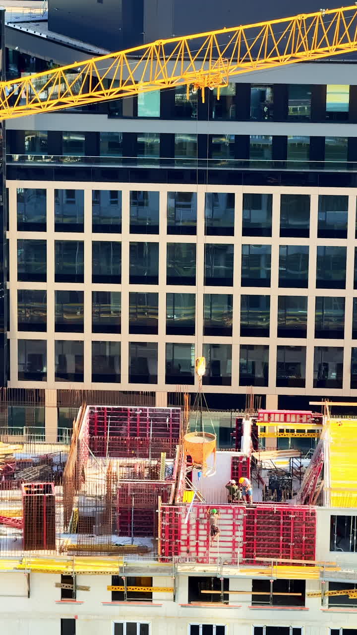 Workers on high-rise site. Workers are actively constructing a high-rise building with cranes and scaffolding in an urban area during daylight