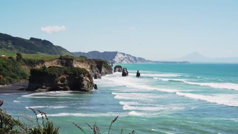 picturesque view of foamy waves on the beach at three sisters and elephant rock in taranaki, new zealand