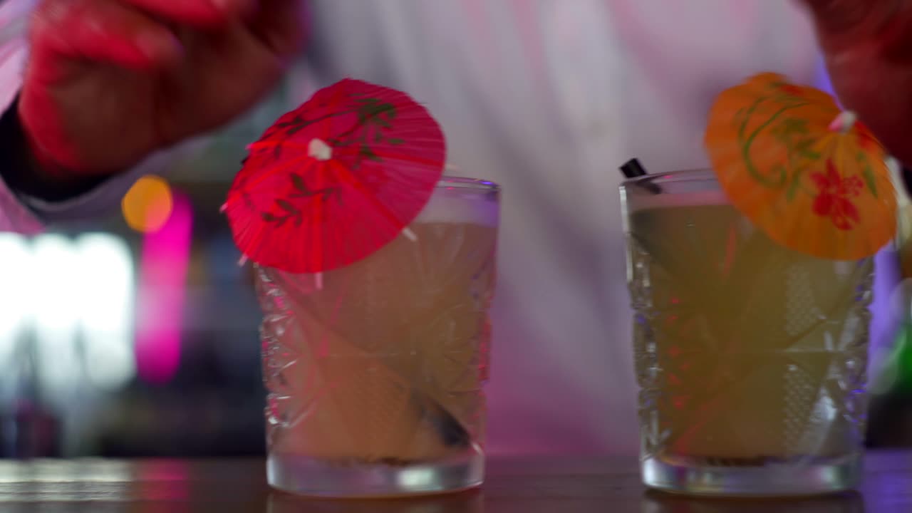 camarero poniendo sombrillas en un cóctel tropical en el mostrador del bar, cerrar