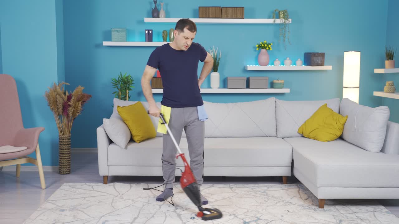 el hombre que tiene dolor en la espalda por la limpieza deja la escoba y comienza a hacer ejercicio y moverse por su espalda.