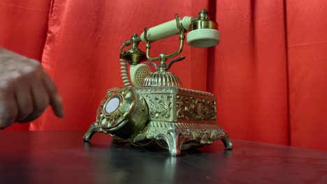 marcar a mano un viejo teléfono rotatorio antiguo en oro con fondo de cortina roja