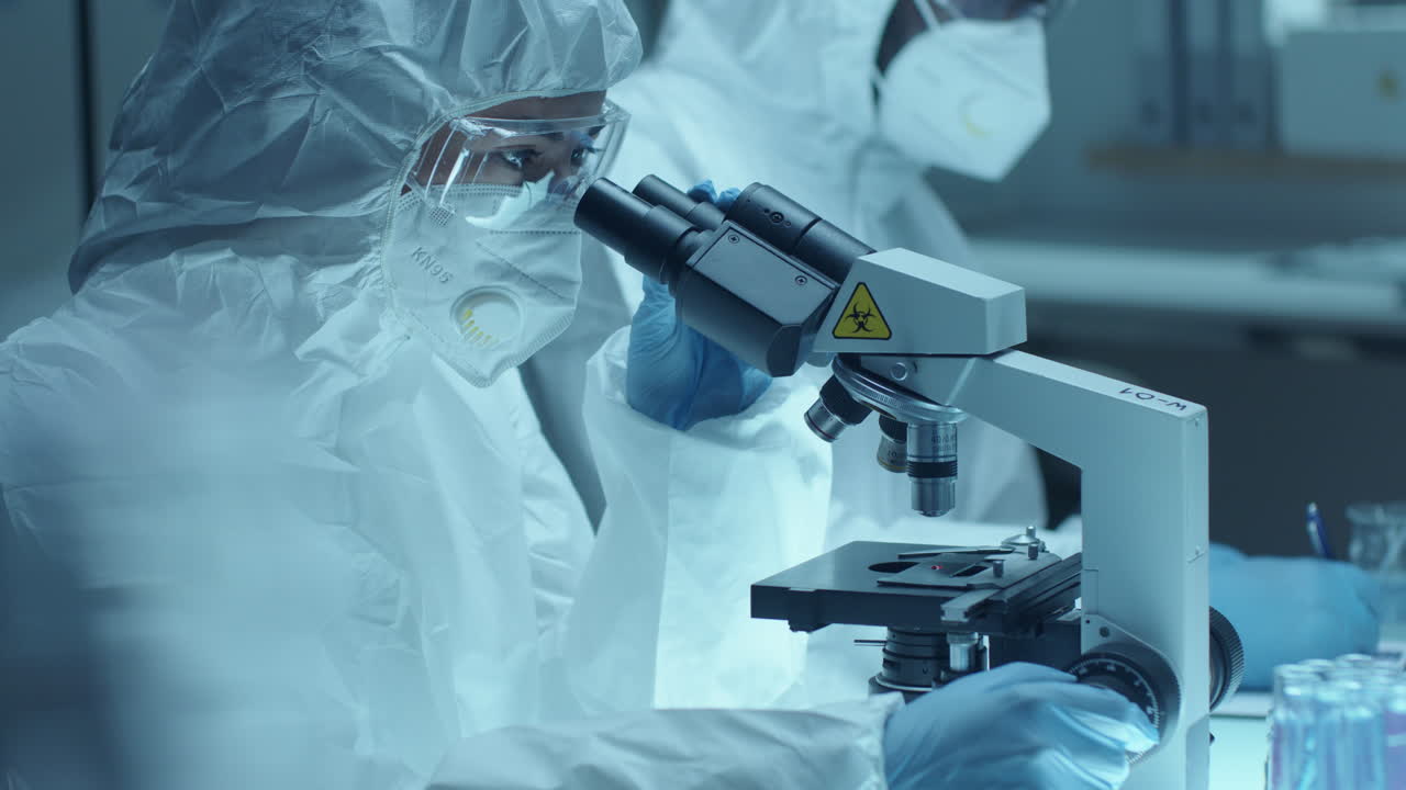 Microbiologist in Protective Uniform Performing Microscopic Examination of Blood
