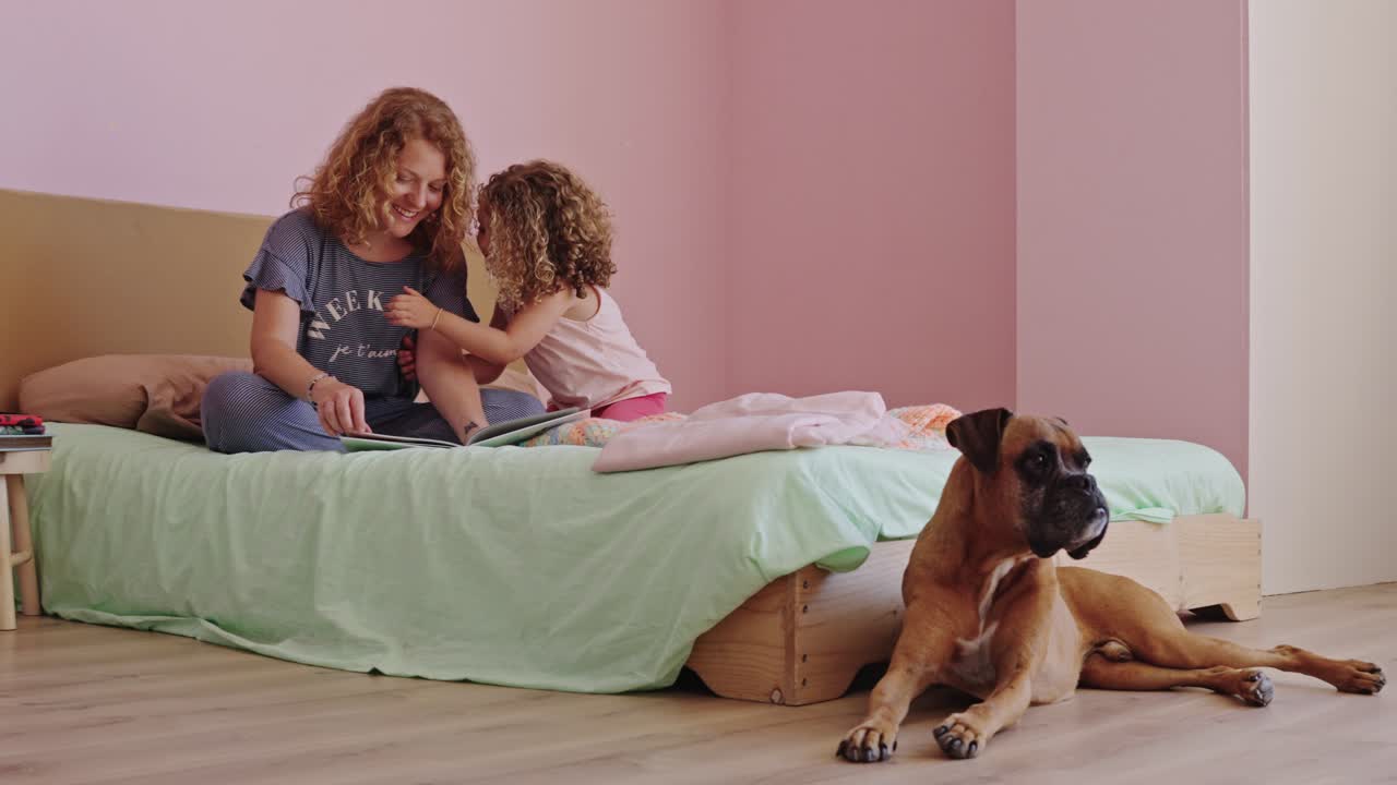Mother and Daughter Reading with Their Dog in Bed