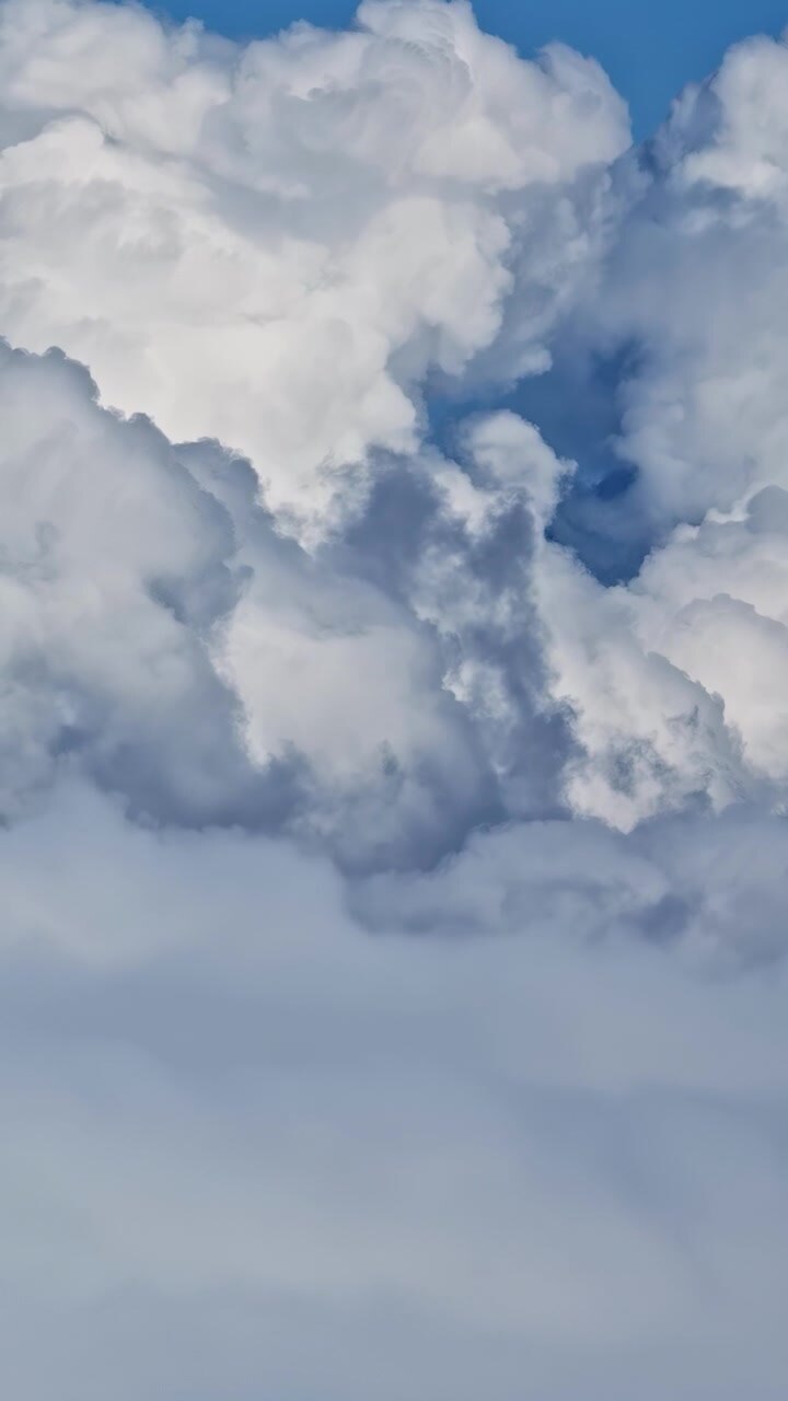 Thick cumulus clouds form intricate patterns against a bright blue sky, creating a dynamic scene. Ideal for weather-related content or atmospheric backdrops.