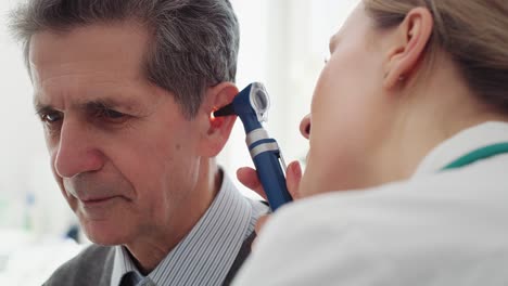 handheld view of female doctor examining ear of senior man