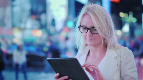 A-Woman-Uses-A-Tablet-On-The-Street-Of-Manhattan-Behind-Her-Pass-The-Famous-Yellow-Cabs---The-Symbol