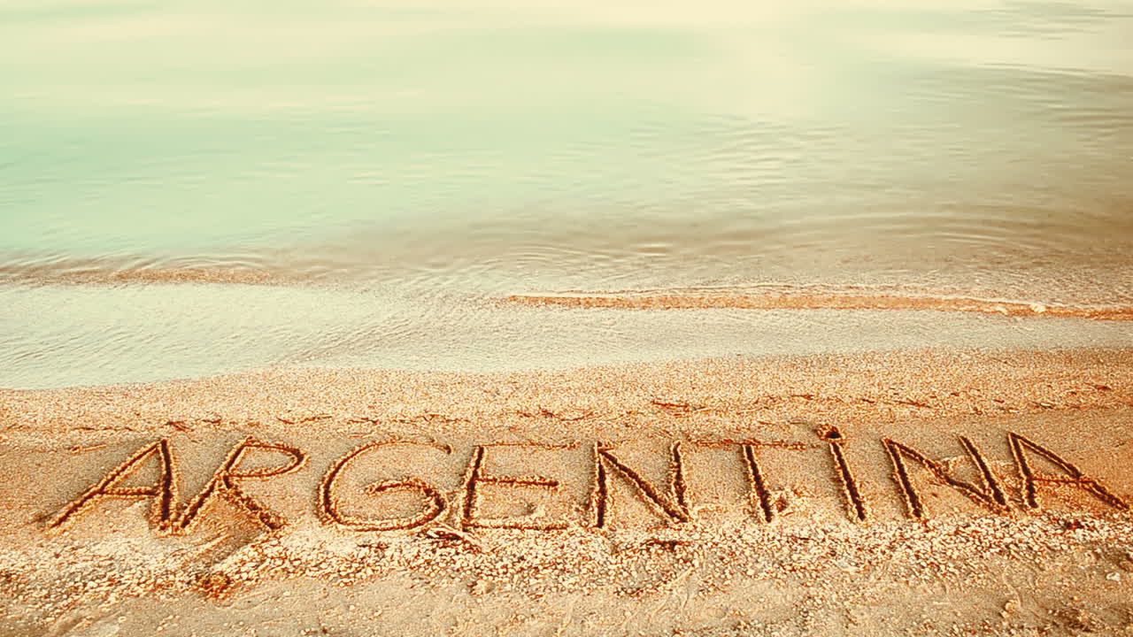 Inskriptionen 'Argentina' i sanden. Inskription på sand, stranden.