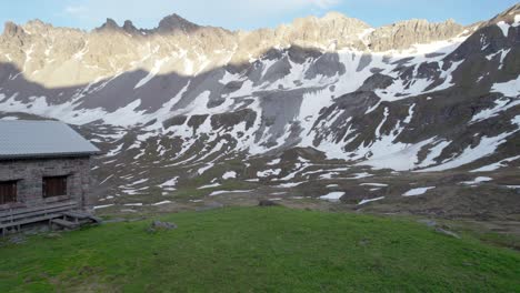 瑞士高山小屋 (swiss alpine hut) 的無人機拍攝的空中影像,揭示了一片壯觀的山地景觀,其中有雪地和高山草原的殘留部分