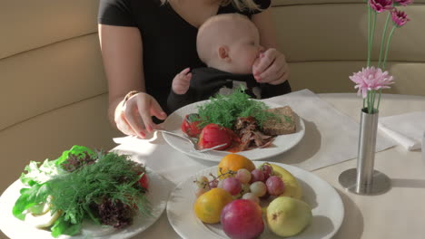 mother with baby daughter having meal in cafe