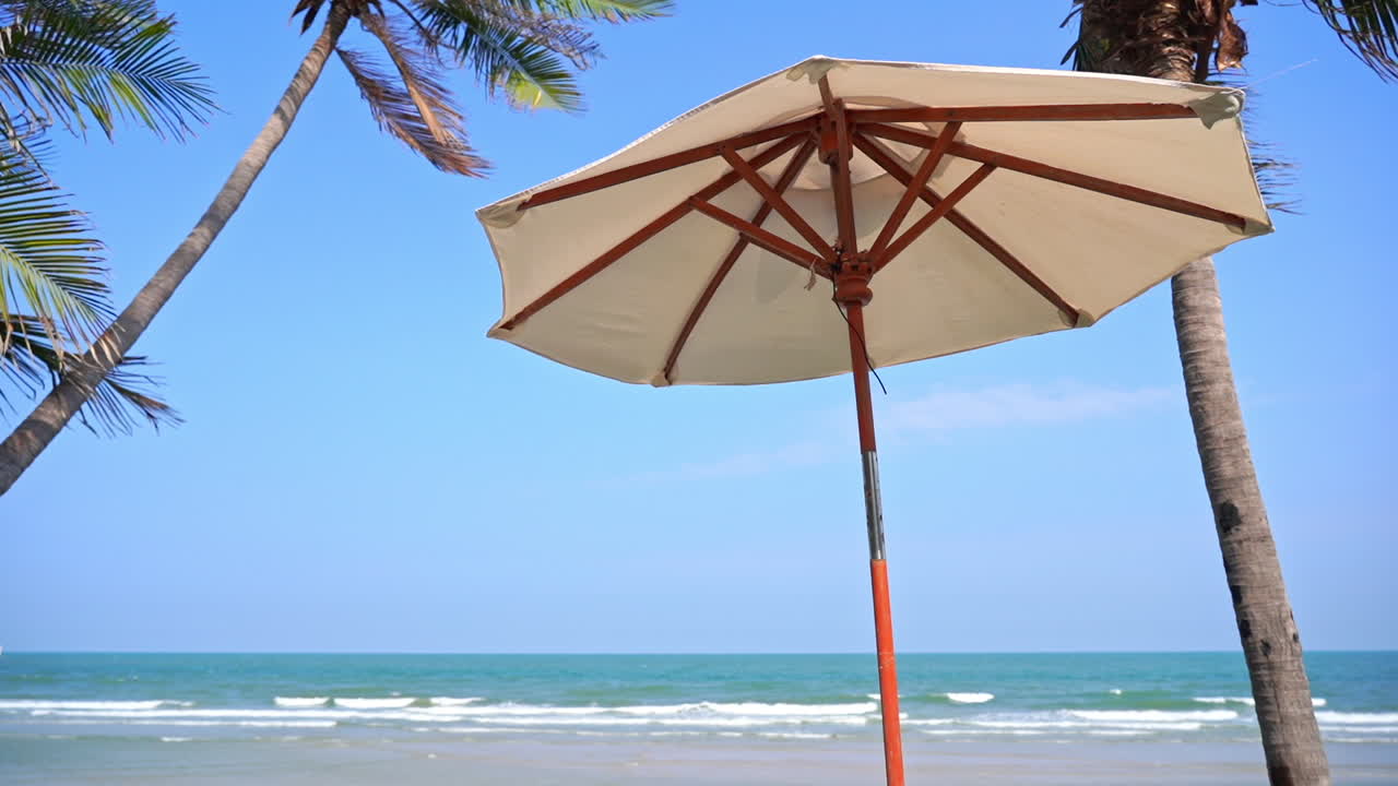 paisaje de vacaciones tropicales, sombrilla de playa bajo palmeras y horizonte azul del océano