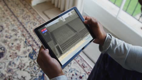 Composite-of-man-sitting-at-home,-watching-athletics-long-jump-event-on-tablet