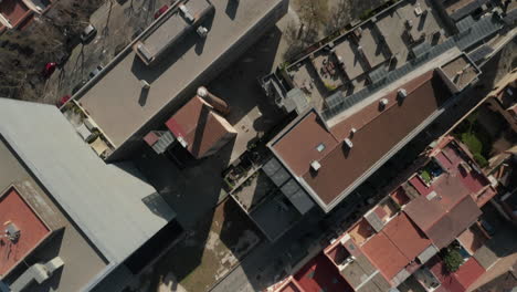 Top-down-panning-footage-of-buildings-in-city.-Fly-above-town-development.-Leafless-trees-in-streets.-Barcelona,-Spain