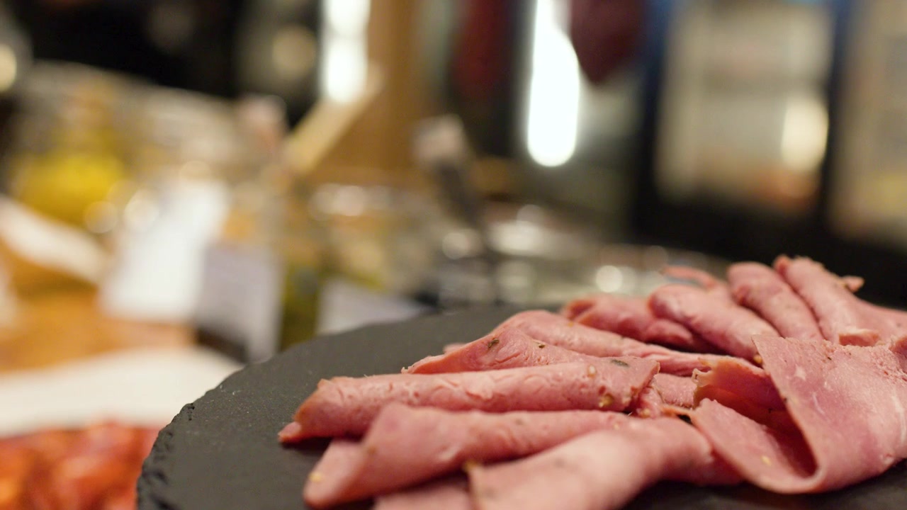 Primo piano di salumi affettati su un piatto da portata nero