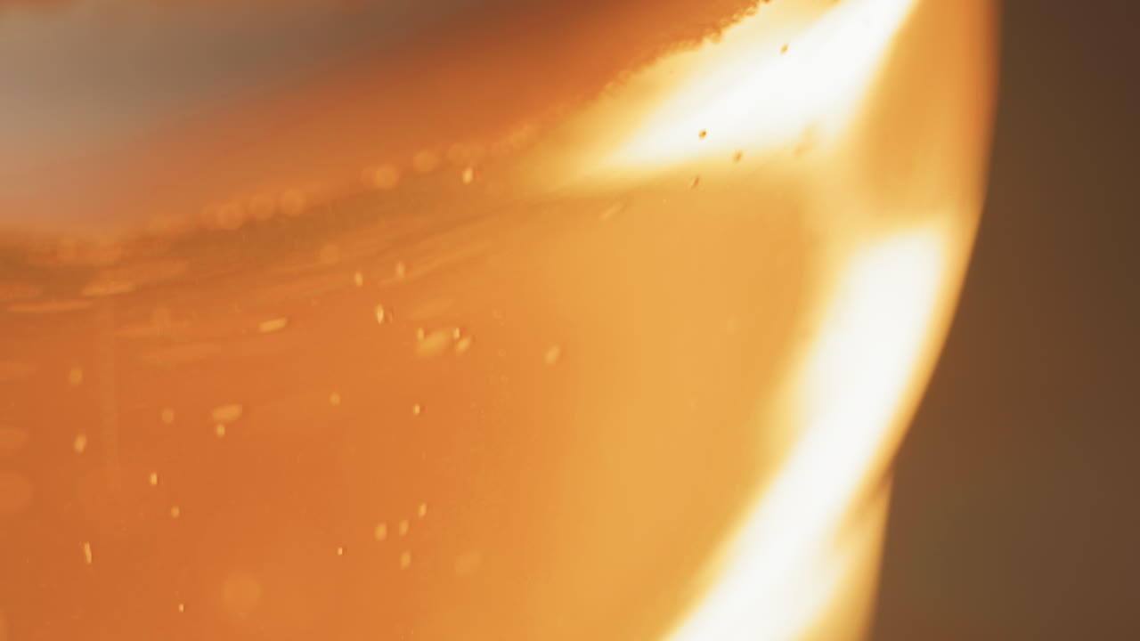 beer bubbles rising to the top of a curved beer glass, with copy space, macro close up