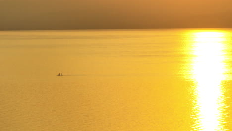 Three-Friends-paddle-board-on-the-lake-during-sunrise-in-the-Sea-of-Galilee,-Israel