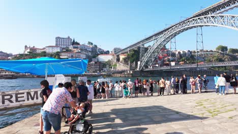 people enjoying a sunny day by the riverside cafes in vila nova de gaia, porto