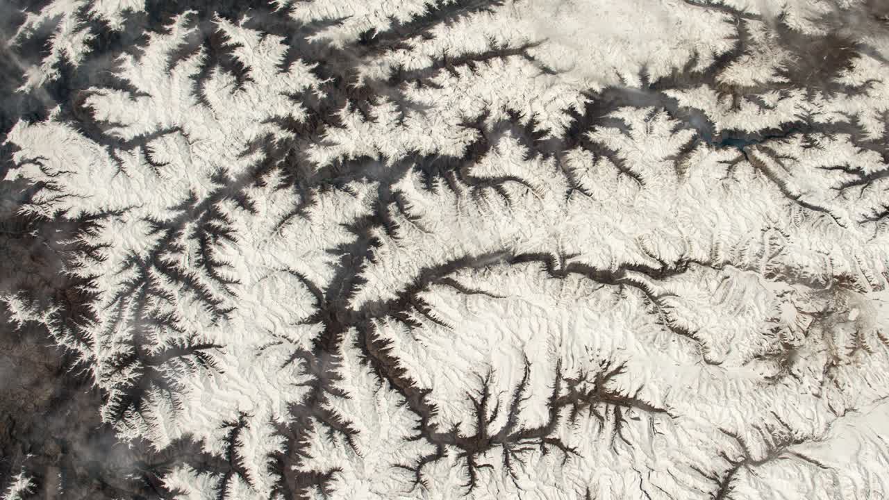 Flying over the earth on the ISS. Flying over the snow-capped mountains, aerial view from space.